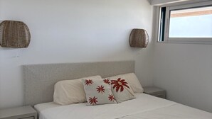 Een slaapkamer met een bed, twee nachtkastjes, een raam en twee wandmanden.