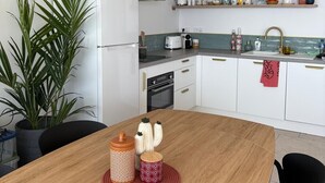Een moderne keuken met witte kasten, een houten eettafel en een hangende lamp.