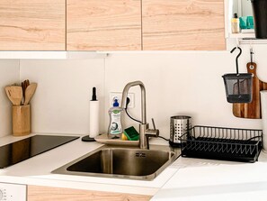 Una cocina moderna con un lavamanos de acero inoxidable, armarios de madera y un colgador para utensilios.