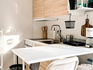 Une cuisine moderne avec un plan de travail blanc, un évier en acier inoxydable et des armoires en bois.