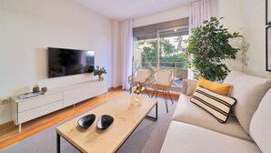 A modern living room with a flat-screen TV mounted on the wall, a wooden coffee table, a beige sofa, and two wicker chairs. - Solaga - Parque Litoral (Málaga)