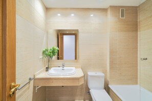 Un baño con lavamanos, inodoro y bañera.