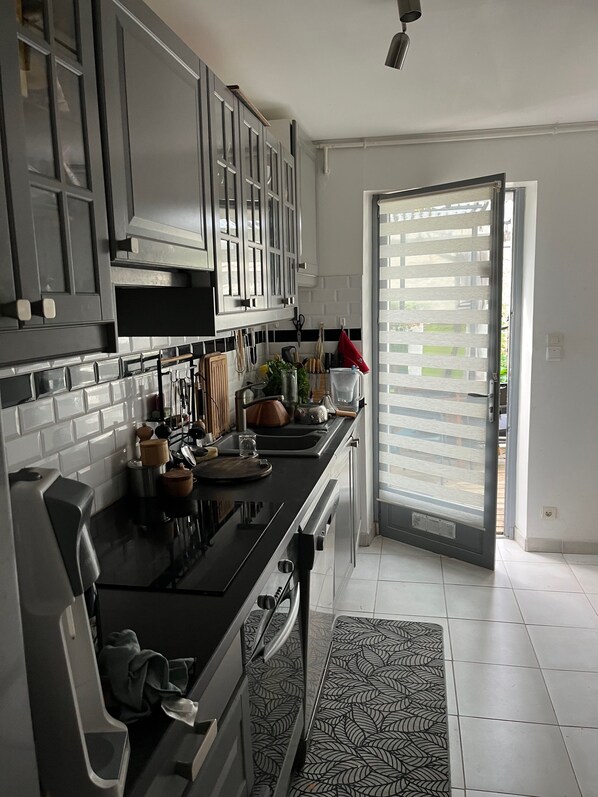 A modern kitchen with grey cabinets, a black countertop, and a patterned rug.