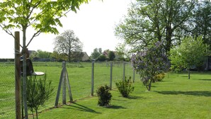 A fenced outdoor area with a grassy field, trees, and a bird feeder. - Charming, peaceful bed & breakfast in the heart of Normandy, in the Eure department (Mesnils-sur-Iton)