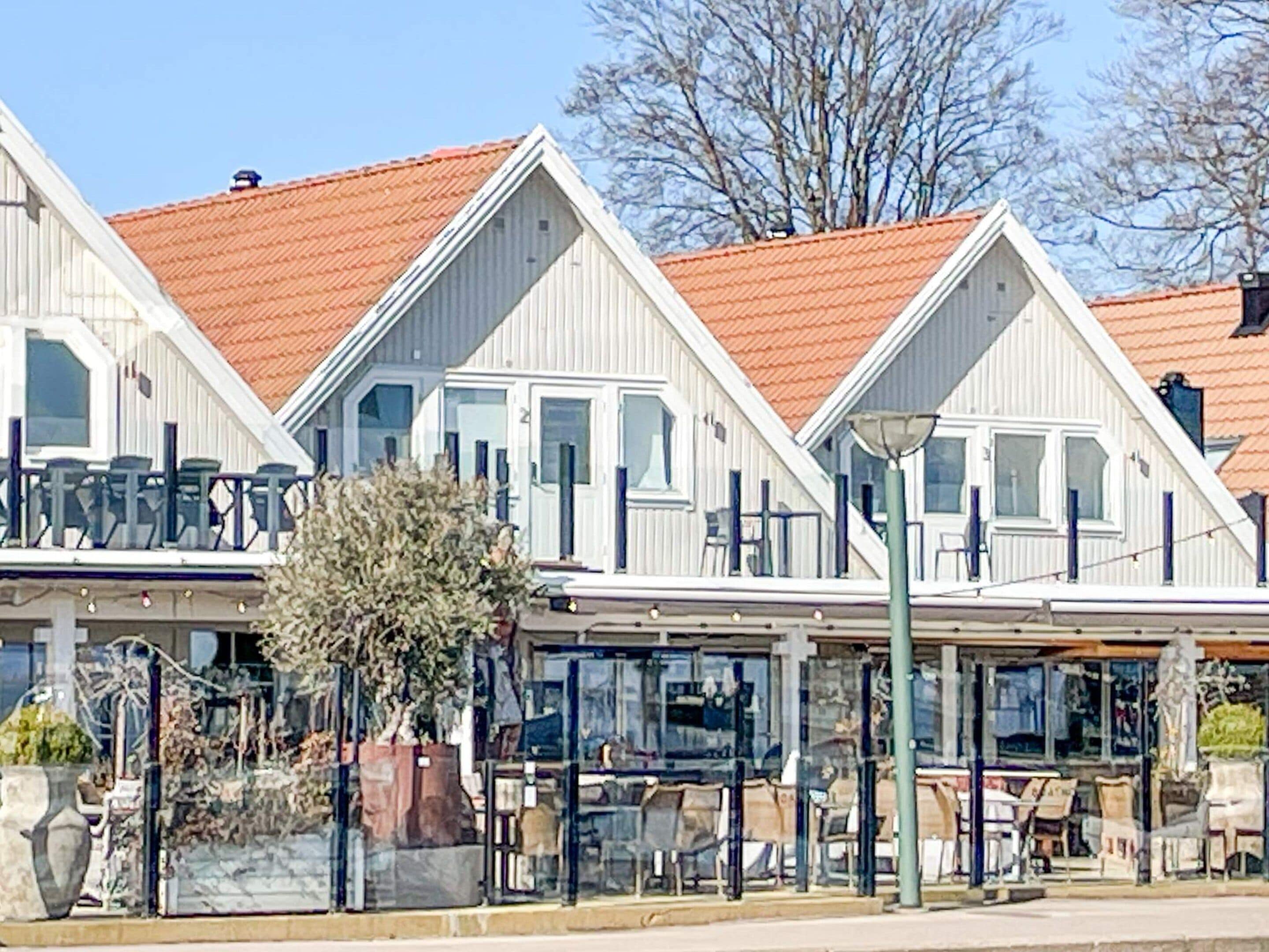 A row of white buildings with red roofs, featuring balconies and outdoor seating areas.