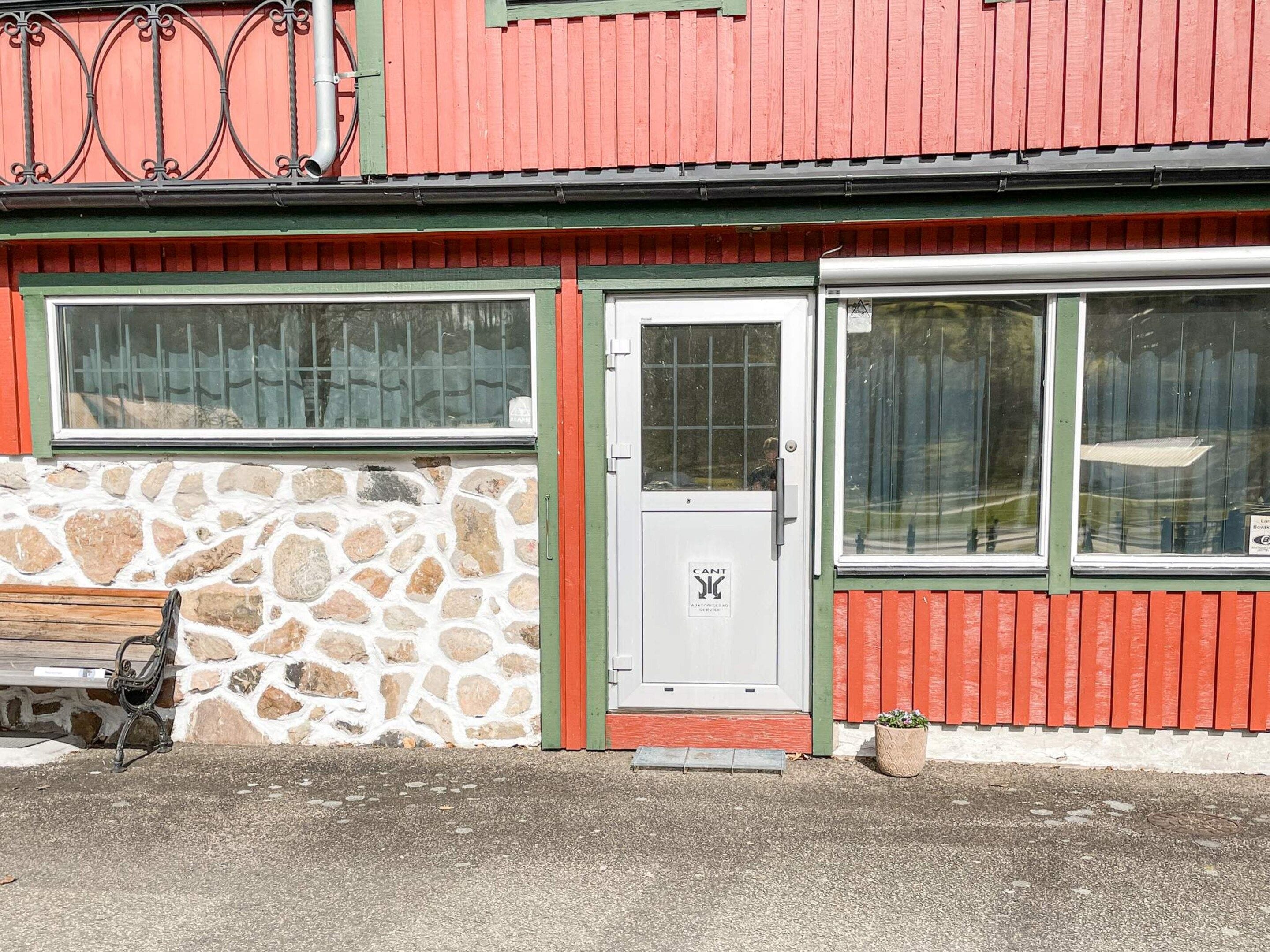 En byggnad med en stenmur, en bänk och en dörr med en skylt.
