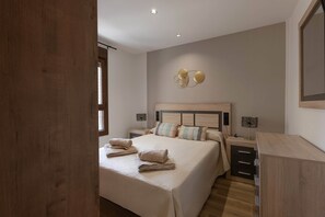 Une chambre à coucher avec un grand lit, des tables de chevet, une tête de lit en bois et un luminaire fixé au mur.