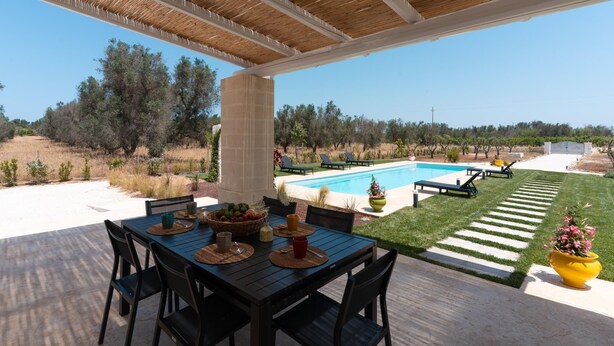 A covered patio with a pool, outdoor seating, and a view of the surrounding landscape. - Lamia Flora con Piscina Privata (Latiano)
