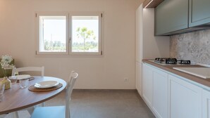 A kitchen with a dining table, chairs, a window, and cabinets. - Lamia Flora con Piscina Privata (Latiano)