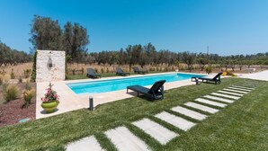 A swimming pool with lounge chairs, a stone structure, and a well-maintained lawn. - Lamia Flora con Piscina Privata (Latiano)