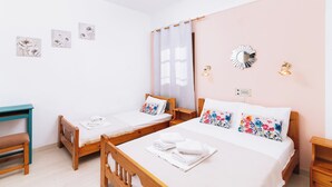 A hotel room with two single beds, a wooden desk, and a small table. - Eva Marina Hotel (Faistos)