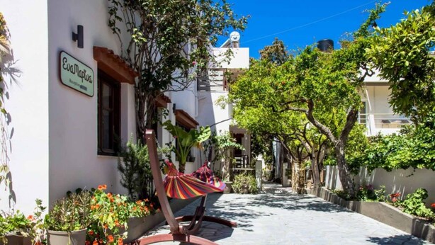 A courtyard with a hammock, potted plants, and a building with a sign reading "Evanova". - Eva Marina Hotel (Faistos)