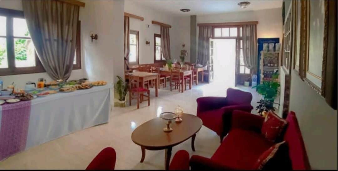Un amplio salón con mesa y sillas de comedor, un sofá rojo y una mesa de centro.