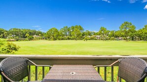 A view from a balcony overlooking a golf course with a clear blue sky.