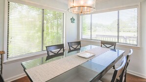 A dining area with a glass table, chairs, and a chandelier.