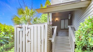 A wooden house with a porch, a staircase, and a gate.
