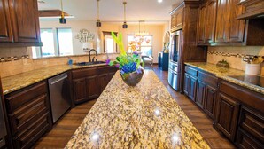 Una cocina con encimeras de granito, armarios de madera y una isla central con un arreglo floral.