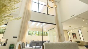 A spacious living area with a high ceiling, modern furniture, and large windows allowing natural light. - Exceptional villa in Marrakech, 10 minutes from the center, private pool, (Marrakech)