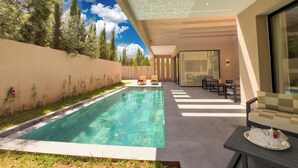 A modern outdoor pool area with a clear blue sky, a pool, and a seating area with a table and chairs. - Exceptional villa in Marrakech, 10 minutes from the center, private pool, (Marrakech)