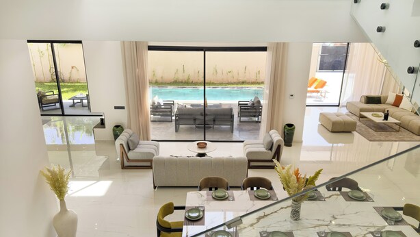 A modern living room with a glass dining table, sofas, and a view of a swimming pool. - Exceptional villa in Marrakech, 10 minutes from the center, private pool, (Marrakech)