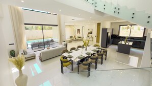 Un salón amplio y moderno con una mesa de comedor para seis personas, un sofá y un ventanal con vistas a una piscina.