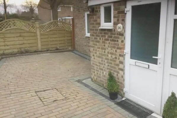 Une maison en briques avec une porte blanche, une petite fenêtre et le numéro « 26 » peint sur le mur.