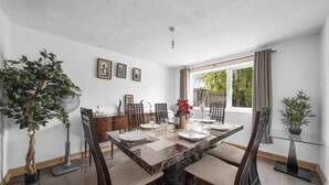 A dining area with a marble table, chairs, and a potted plant. - 5 Bed House - Sleeps 10 - Garden - Parking - Wifi (Aylesford)