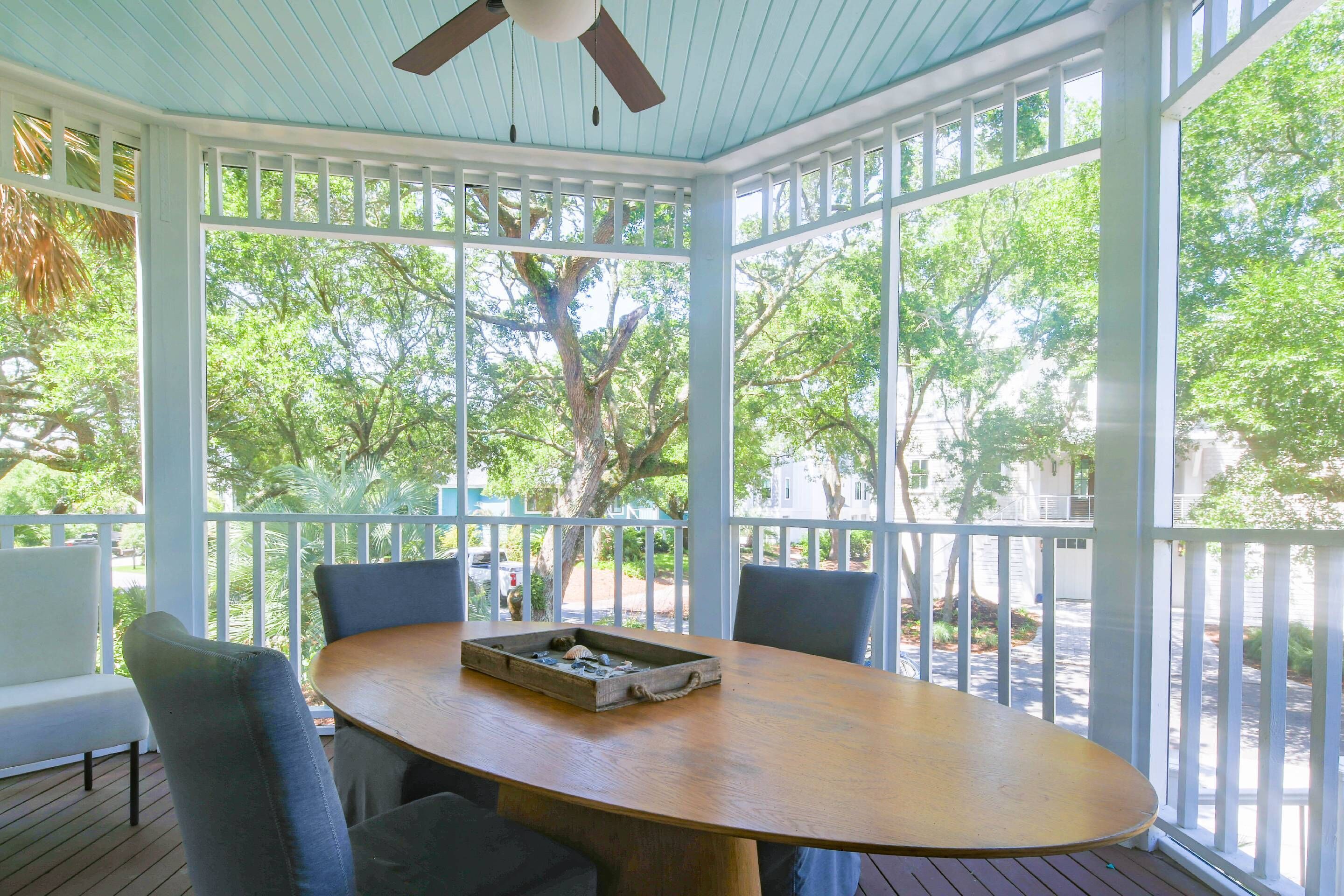 A covered outdoor dining area with a wooden table, chairs, and a ceiling fan.