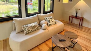 A modern living room with a beige sofa, two side tables, and a wooden floor.