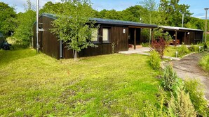 A modern two-story building with a dark exterior, a covered porch area, and a well-maintained lawn.