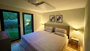 A bedroom with a large bed, two bedside tables, a ceiling light, and two framed pictures on the wall.