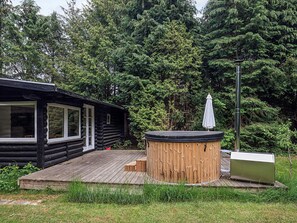 A log cabin with a hot tub and an umbrella on a wooden deck. - 6 Person Holiday Home in Idestrup (Idestrup)