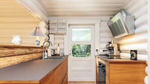A compact kitchen with wooden cabinetry, a built-in stove, and a window overlooking greenery.