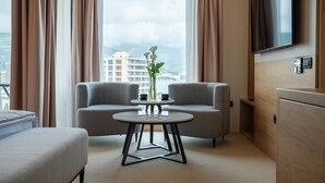 Ein modernes Hotelzimmer mit einer Couch, einem kleinen runden Tisch und einem an der Wand montierten Fernseher.