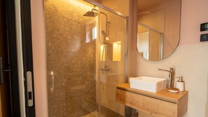 Ein modernes Badezimmer mit einer Duschkabine aus Glas, einem Holzbadezimmer-Möbel und einem runden Spiegel.