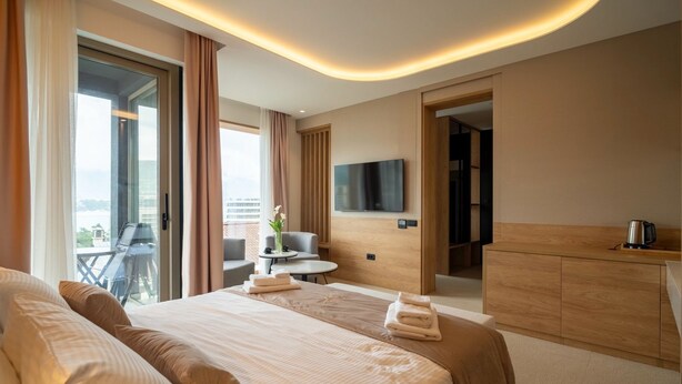 Ein Hotelzimmer mit einem großen Bett, einem Schreibtisch, einem Sessel, einem Flachbildfernseher und Blick ins Freie.