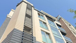 Ein mehrstöckiges Gebäude mit modernem architektonischen Design, das große Fenster und ein markantes vertikales Element an der Fassade zeigt.
