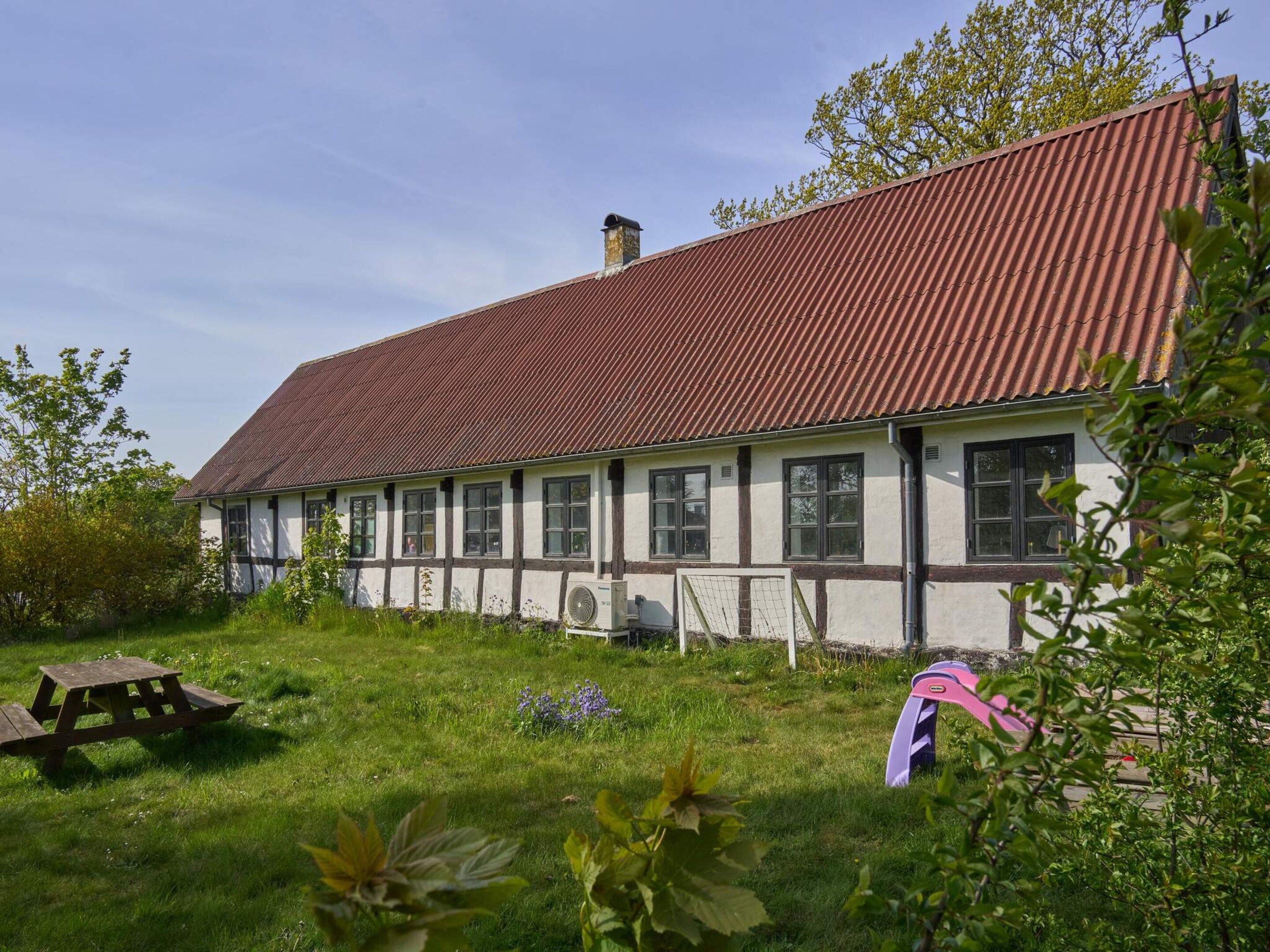 A two-story building with a red roof, white walls, and dark trim.