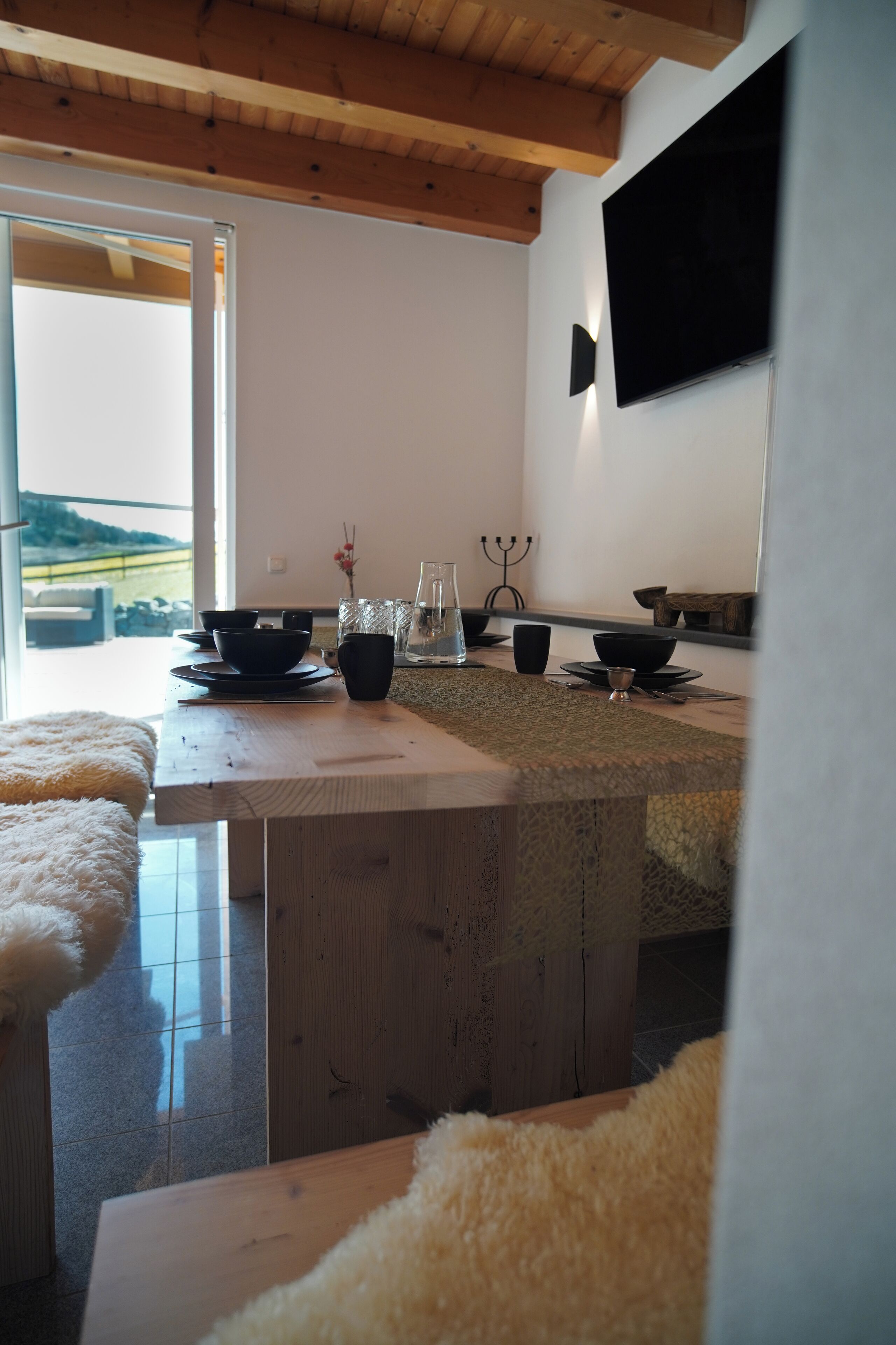 Una cocina moderna con una isla de madera, un ventanal grande y un televisor de pantalla plana montado en la pared.