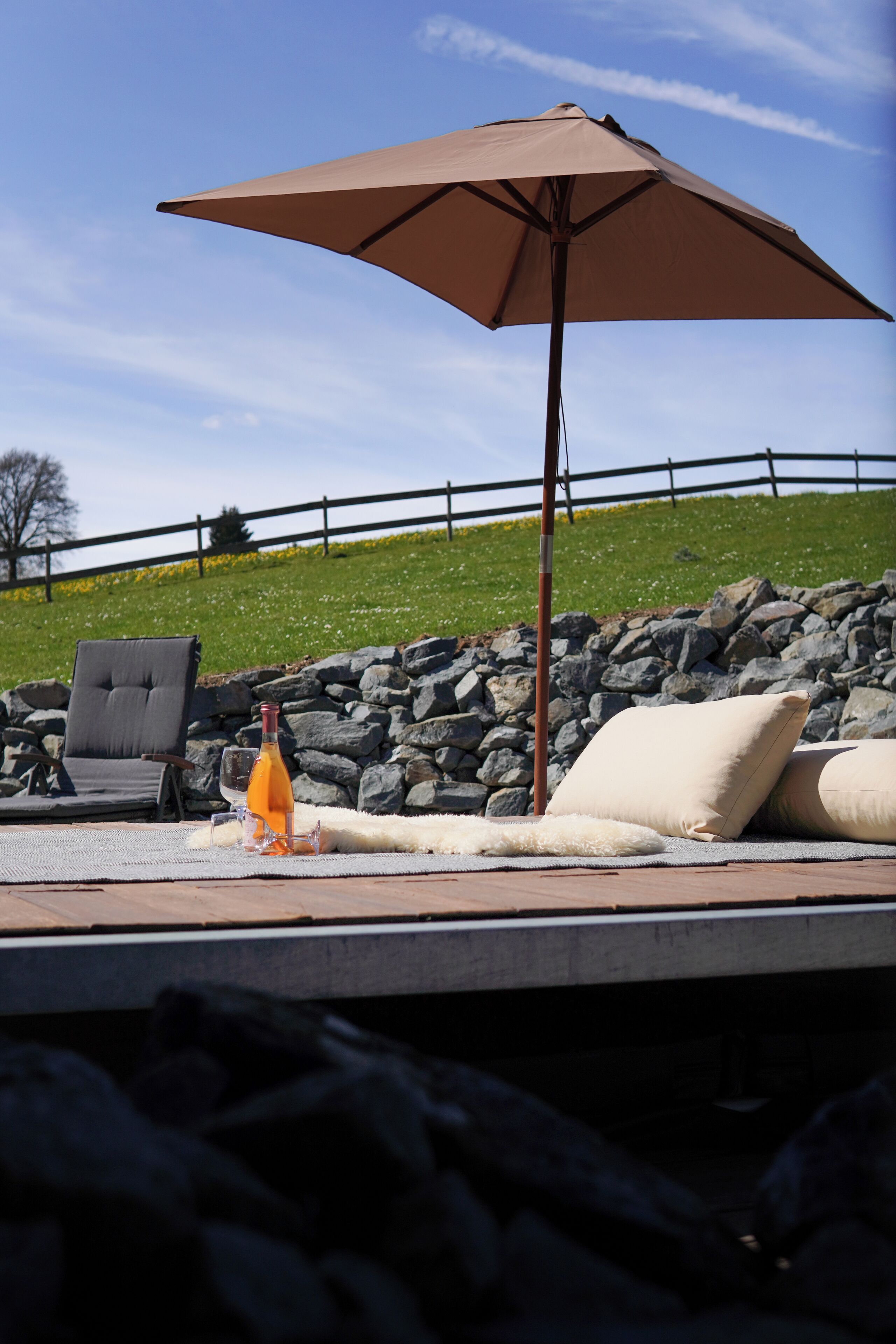 Ein Poolbereich mit Liegestuhl, einer Orangensaftflasche und einem großen Sonnenschirm.