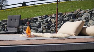 Ein Poolbereich mit Liegestuhl, einer Orangensaftflasche und einem großen Sonnenschirm.