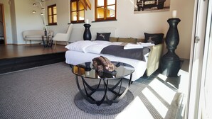 A modern bedroom with a glass coffee table, a sofa, and a bed with white linens. - Alpen Lodges Gindels - Space for 10 - (Rettenberg)