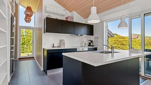 A modern kitchen with a large island, black cabinets, white countertops, and pendant lighting. - "Kody" - 400m from the sea by Interhome (Ebeltoft)
