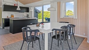 A modern kitchen with a central island, black chairs, and a white dining table. - "Kody" - 400m from the sea by Interhome (Ebeltoft)