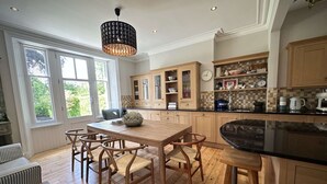 Una cucina moderna con mobili in legno, un'isola centrale con sgabelli e un'ampia finestra che permette l'illuminazione naturale.