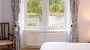 Una camera da letto con una grande finestra, una sedia di legno, un termosifone e un letto.