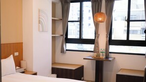 A hotel room with a bed, bedside table, a small desk with a lamp, a bench, and a window with curtains. - Yǒu mǒu hostel (Tainan)
