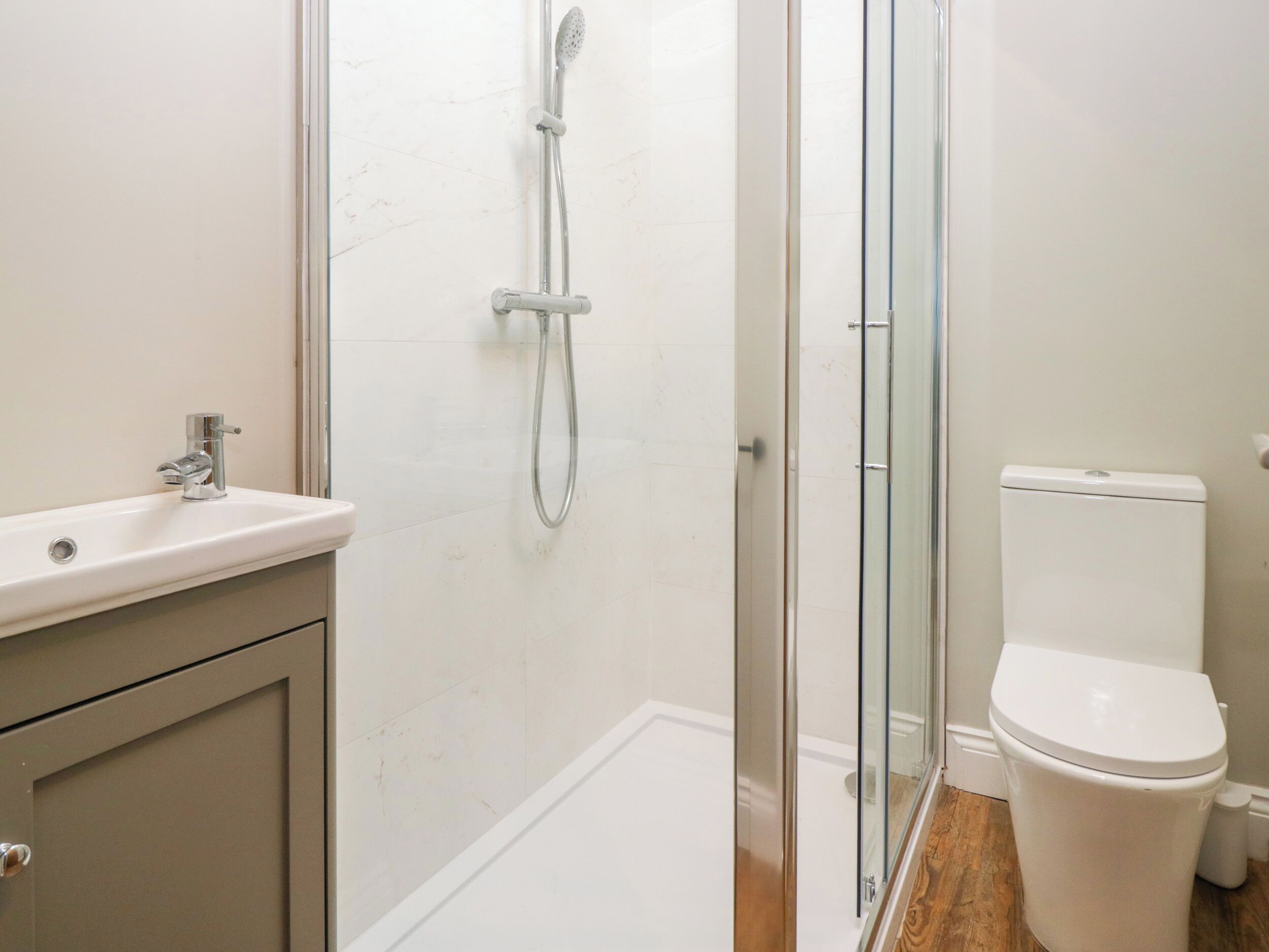 Een badkamer met douche, toilet en wastafel.
