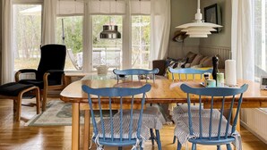 A dining area with a wooden table and blue chairs, a black chair, and a sofa with cushions. - 4 Star Holiday Home in Norrtalje (Norrtälje)
