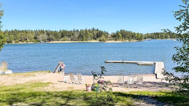 A lakeside view with a dock, chairs, and a lifebuoy on the shore. - 4 Star Holiday Home in Norrtalje (Norrtälje)